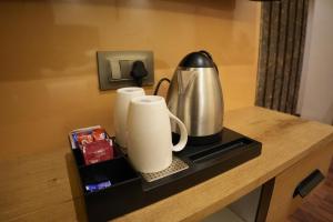 a counter with a coffee pot and cups on it at Trevon Twin Tree Inn in Dhanbād
