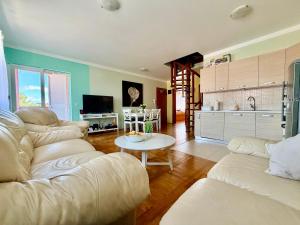 a living room with two white couches and a kitchen at Apartment Andrea in Mirce