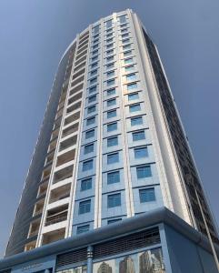 a tall white building with a blue sky in the background at Relaxing bed Ajman in Ajman  +2 photos