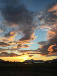 a sunset with a cloudy sky in a field at Vacation Home Fagravik in Akureyri