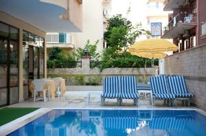 two chairs and an umbrella next to a swimming pool at Belle Ocean Apart Otel in Alanya