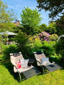 two chairs sitting in the grass in a garden at Komfort-Fewo mit Infrarotsauna & WLAN nahe Sorpesee - Haus am Krähenbach - Steinert in Sundern