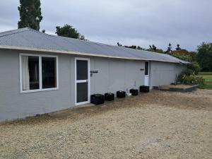 a white building with potted plants in front of it at The Big Chook Accommodation in Waianakarua