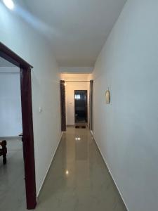 a hallway with white walls and a hallway leading to a door at Kuttikkanam stay in Pīrmed