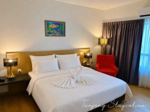 a bedroom with a large white bed with a red chair at Tunjong Stay in Kota Bharu +13 photos