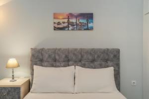 a bed with a gray headboard and a picture above it at Comfy Apt next to metro in Athens +7 photos