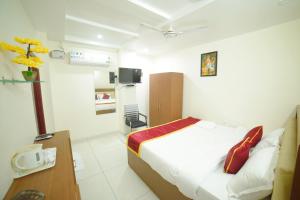 a bedroom with a bed and a desk and a tv at The EMBASSY HOTEL in Guntūr