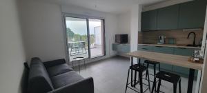 a living room with a couch and a kitchen at L'Appar-TMN in Challans