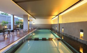 a swimming pool with a table and chairs in a building at Hotel Santika Bengkulu in Bengkulu