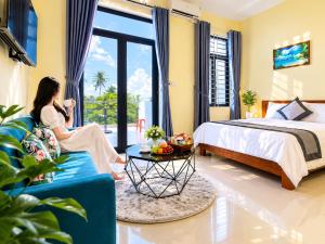 a woman sitting on a couch in a room with a bed at Sontra Sea Hotel in Danang +79 photos