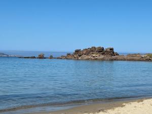 a body of water with a beach and some rocks at casa vacanze AG in Portoscuso