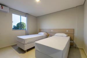 two beds in a small room with a window at WR Confort Hotel Campo Grande in Campo Grande