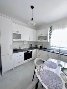 a kitchen with white cabinets and a table with chairs at Noméa - Modern Apartment Aigio in Aigio +7 photos