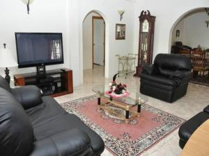 sala de estar con muebles de cuero negro y TV de pantalla plana en Windmill Villa, en Craighton