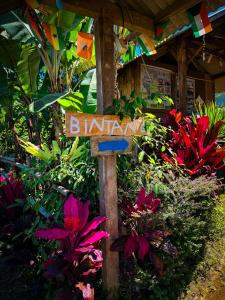 a sign in the middle of a garden with flowers at Bintang Homestay in Tetebatu