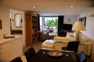 uma sala de estar com um sofá e uma pessoa sentada numa cadeira em Sunny Glen Cottage em Waikanae