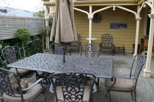 una mesa y sillas con una sombrilla en el patio en Villa Rouge B&B, en Invercargill