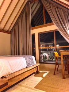 a bedroom with a bed and a table and a window at Kuda Putih Guest House Pandawa in Ungasan +56 photos