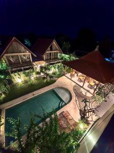 a house with a swimming pool at night at Kuda Putih Guest House Pandawa in Ungasan