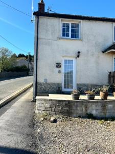 a house with potted plants in front of a street at Cosy Cottage in Garnant in Garnant