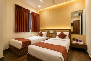 a hotel room with two beds and a window at Hotel Shiv Shakti in Rajkot