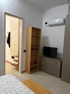 a bedroom with a bed and a dresser with a television at Casa sole Sicilia in Alcamo