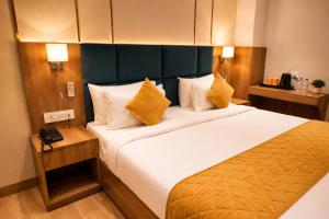 ein Hotelzimmer mit einem großen Bett und gelben Kissen in der Unterkunft Hotel Three Seasons in Vrindāvan + 136 Fotos