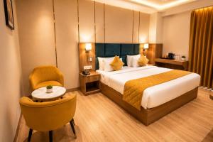 ein Hotelzimmer mit einem Bett und einem Stuhl in der Unterkunft Hotel Three Seasons in Vrindāvan