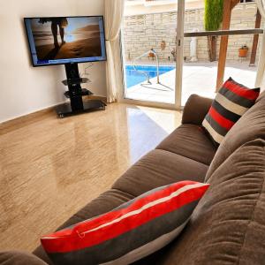 a living room with a couch and a tv at Villa Athena in Peyia