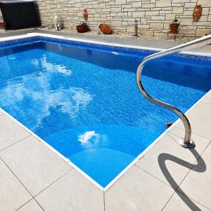 a blue swimming pool with a metal rail next to it at Villa Athena in Peyia