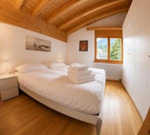a bedroom with a large white bed with wooden ceilings at Residenz Darianne Leukerbad in Leukerbad