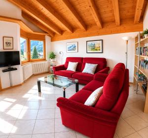 a living room with a red couch and a glass table at Residenz Darianne Leukerbad in Leukerbad