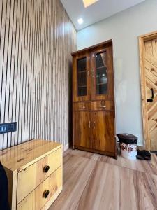 a room with a wooden dresser and a wooden door at Ekantam Mountain Cottages in Dehradun