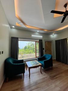 a living room with two chairs and a table and a window at Ekantam Mountain Cottages in Dehradun