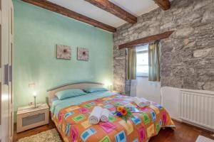 a bedroom with a bed and a stone wall at Tourist Farm Pri Živcovih in Dutovlje