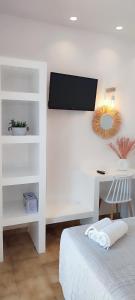 a white bedroom with a bed and a desk at Maria Studios in Parikia