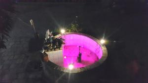 une piscine violette avec des gens debout autour de elle la nuit dans l'établissement Hotel Bishram, à Pokhara