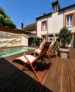 two chairs sitting on a deck next to a swimming pool at Maisons Sauvages - Piscine & Jacuzzi - Proche Zoo de Beauval & Châteaux in Romorantin