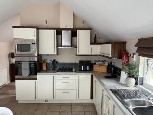 a kitchen with white cabinets and a microwave at caddys lodge in Tydd Saint Giles