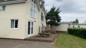 a patio with a picnic table in front of a house at caddys lodge in Tydd Saint Giles