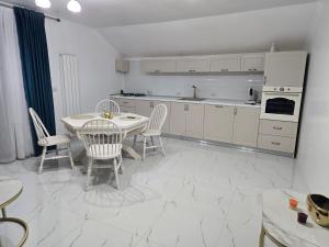 a white kitchen with a table and chairs in it at Casa Roberto in Budeşti