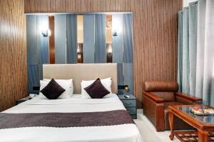 a bedroom with a bed and a chair and a table at Hotel Rivlet By Carlton Suites in Gurgaon +47 photos