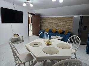 a living room with a white table and chairs and a blue couch at Casa Roberto in Budeşti