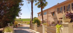 a gate to a house with palm trees and a vineyard at Le Moulin du Comte - chambres privées en gîte in Bourrouillan