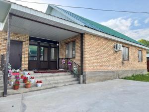 a brick house with a porch with potted plants at Hostel Hanysha in Kazarman