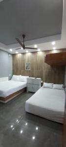 a bedroom with two beds and a ceiling fan at Hyton Grand - Kilambakkam in Urapakkam