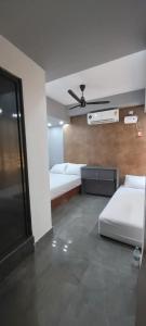 a room with two beds and a ceiling fan at Hyton Grand - Kilambakkam in Urapakkam +1 photo