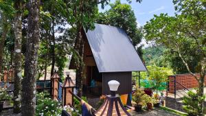 a small house with a grey roof in a garden at SPATHODEA in Vagamon