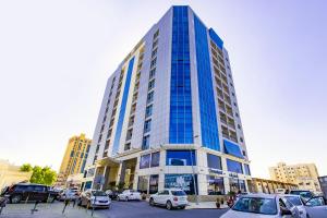 een hoog gebouw met auto's geparkeerd op een parkeerplaats bij Imperial Suites Hotel in Doha