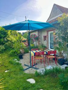a blue umbrella with two tables and chairs under it at La Maisonnette in Cellettes